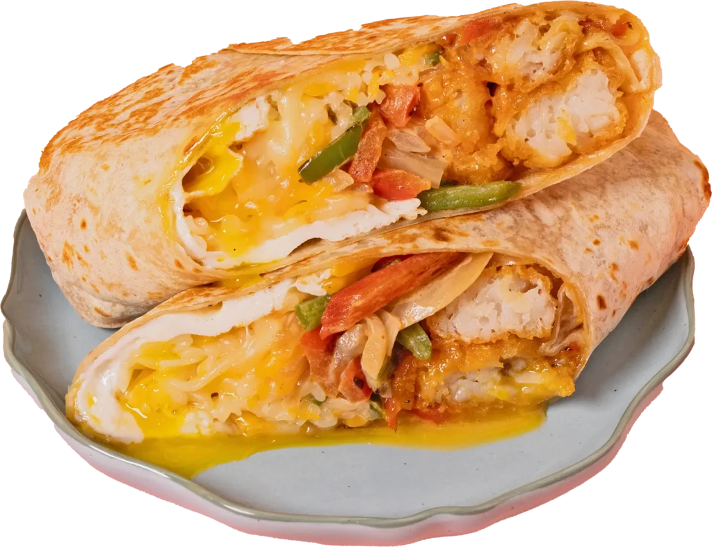 Two halves of a toasted burrito stacked on a plate, showing melted cheese, eggs, peppers, and crispy fillings.